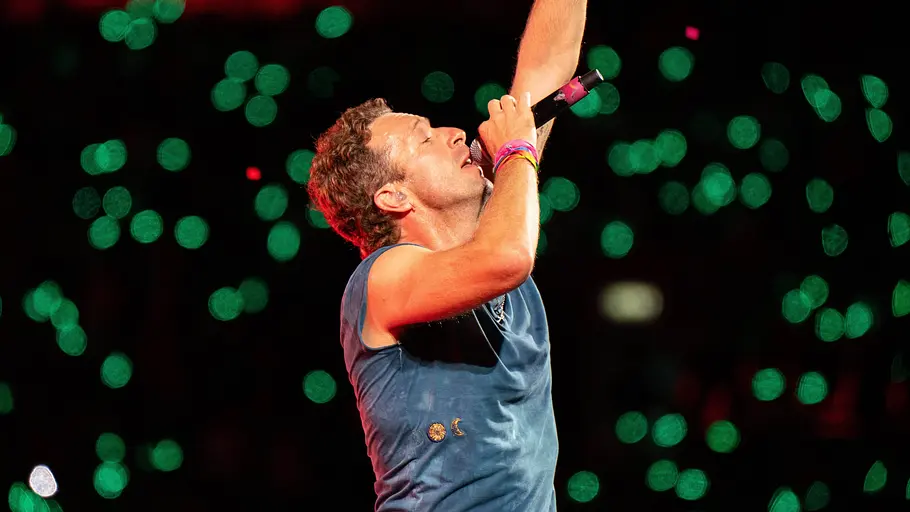 Coldplay Chris Martin Chris Martin singt, hält den rechten Arm hoch und schließt dabei die Augen.