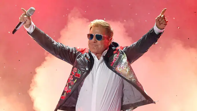 Dieter Bohlen beim Auftritt. Beide Arme nach oben gestreckt, ein Mikro in der Hand. - Foto: IMAGO / Panama Pictures Dieter Bohlen beim Auftritt. Beide Arme nach oben gestreckt, ein Mikro in der Hand. - Foto: IMAGO / Panama Pictures