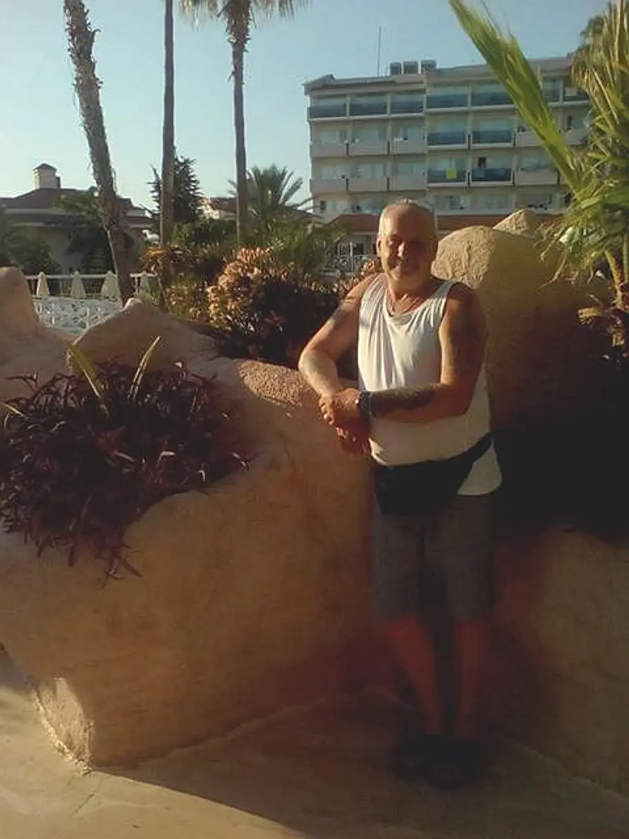 Dieter Wollny heute. Ein privates Urlaubsfoto zeigt ihn im weißen Unterhemd vor Palmenkulisse