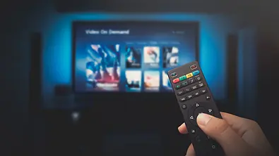 Eine Fernbedienung, im Hintergrund das Streaming Menü eines TV - Foto: Canve