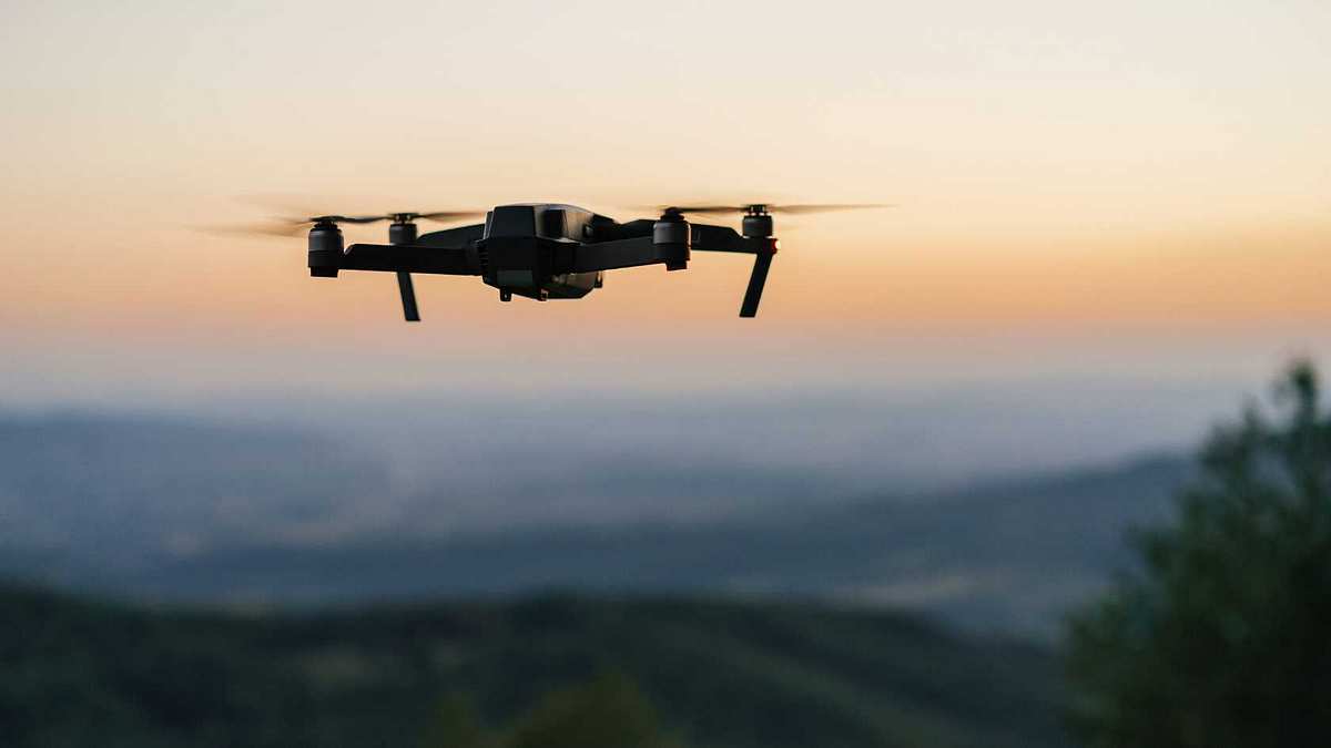 Eine Drohne fliegt am Horizont bei Sonnenuntergang