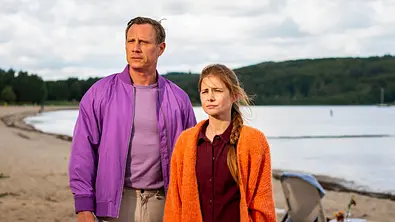 Am Sandstrand stehen Dr. Nice (Patrick Kalupa) und Charlie (Josefine Preuß) nebeneinander. Beide schauen mit traurigen Blick seitlich nach vorne. - Foto: © ZDF/Gordon Muehle Am Sandstrand stehen Dr. Nice (Patrick Kalupa) und Charlie (Josefine Preuß) nebeneinander. Beide schauen mit traurigen Blick seitlich nach vorne. - Foto: © ZDF/Gordon Muehle