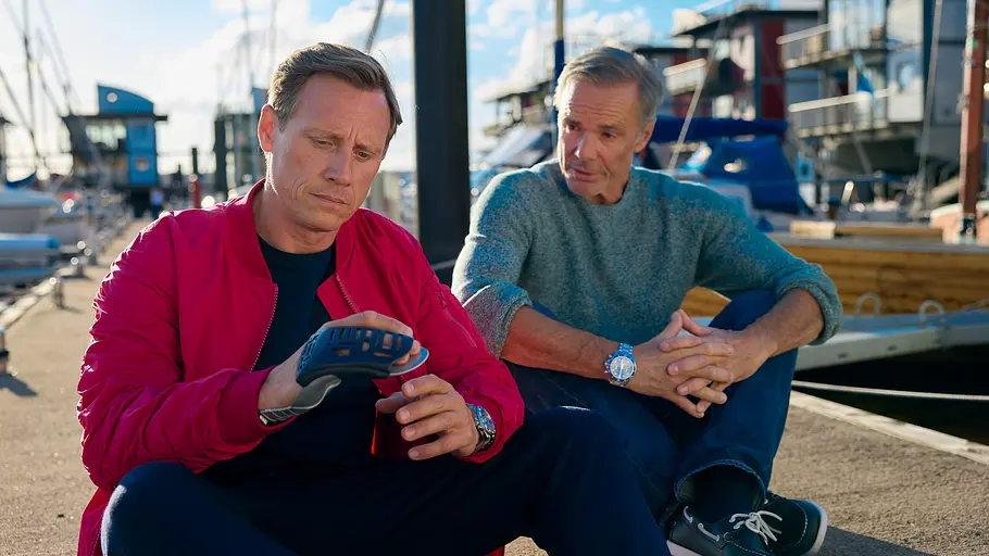 Dr. Nice: „Das wahre Gesicht“ Im Hafen auf einem Anleger sitzen Dr. Nice (Patrick Kalupa) und Dr. Clemens Jörgensen (Hannes Jaenicke) dicht nebeneinander im Schneidersitz.