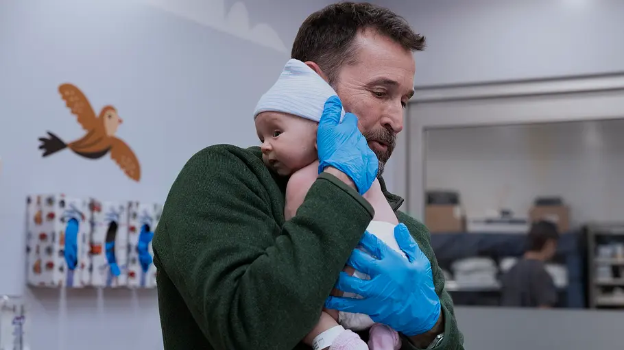 Dr. Robby hält ein Baby.