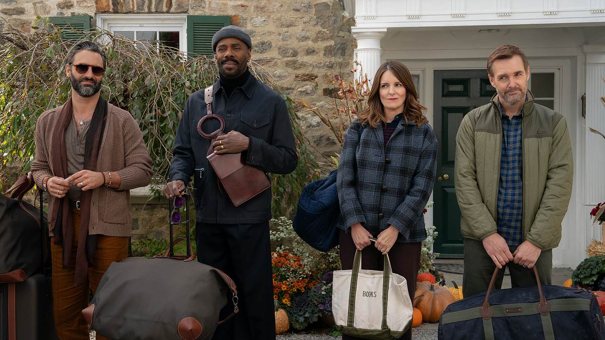 Drei Paare verreisen viermal im Jahr in „The Four Seasons“. Drei Männer und eine Frau stehen mit Taschen und Koffern vor einem Haus.