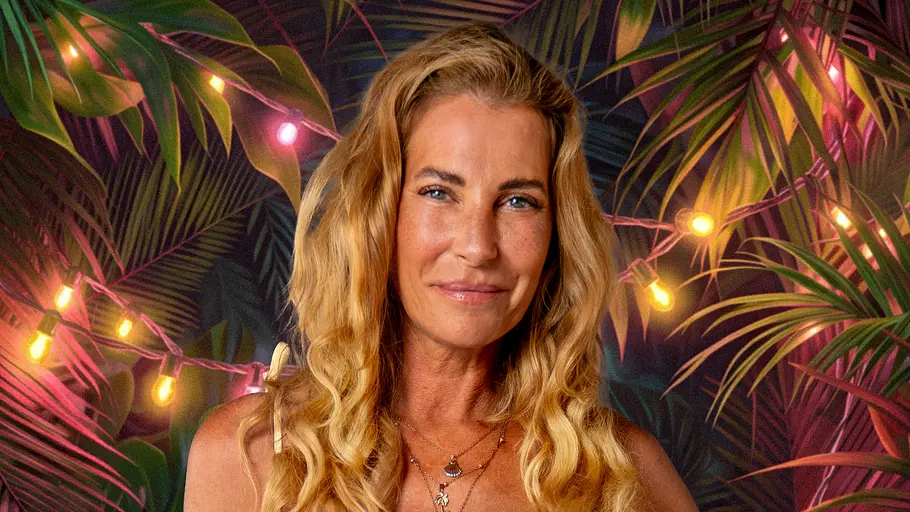 Reality-TV-Star Giulia Siegel posiert für ein Promobild von „Dschungel Divas“ in einem hellgelben Kleid vor einer tropischen Kulisse mit Lichterketten und üppigen Pflanzen. Sie lächelt in die Kamera und hat eine Hand in die Hüfte gestützt.