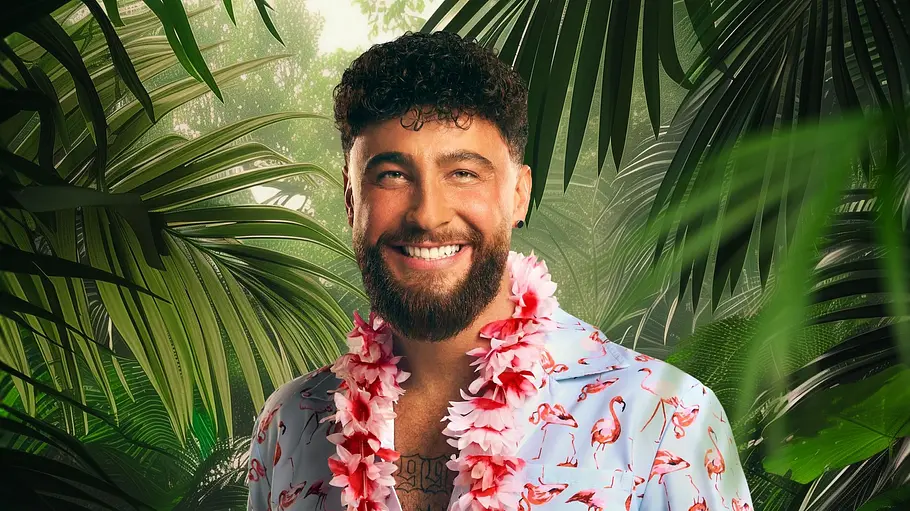 Mann mit Bart und Locken lächelt in tropischer Kulisse, trägt ein hellblaues Flamingo-Hemd, schwarze Shorts und eine pinke Blumen-Girlande; der Dschungel-Hintergrund ist KI-generiert.