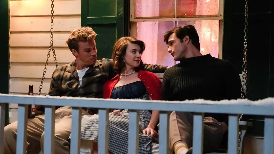 Muriel, Lee und Julius sitzen auf einer Veranda und unterhalten sich. Beide Männer schauen Muriel an.
