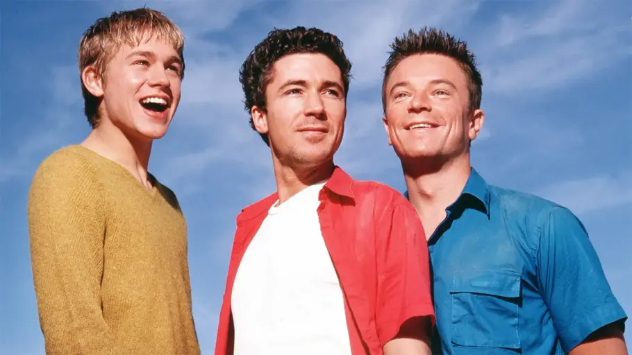 Stuart, Vince und Nathan stehen vor einen bewölkten Himmel und lächeln