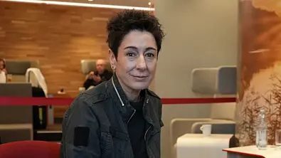 In einer Lounge sitzt Dunja Hayali und schaut in die Kamera. - Foto: ZDF/Felix Korfmann