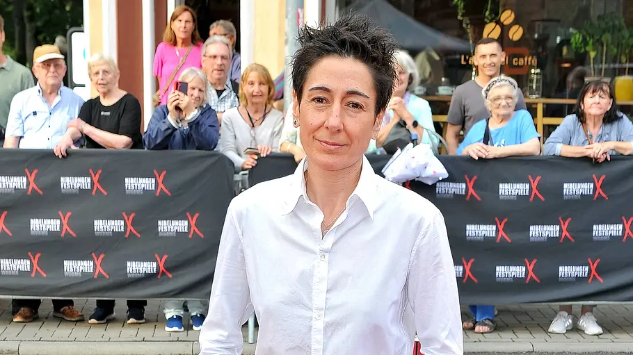Dunja Hayali teilt offen, was sie bewegt. Dunja Hayali schaut in die Kamera, hinter ihr stehen Zuschauer.