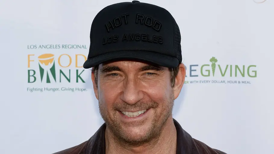 Dylan McDermott lacht auf dem roten Teppich. Er trägt eine schwarze Kappe.