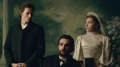 Chalres steht in East of Eden im dunkle Anzug neben seinem Bruder Adam und dessen Frau Cahty, die im Brautkleid zu ihm herüberschaut. - Foto: Netflix Chalres steht in East of Eden im dunkle Anzug neben seinem Bruder Adam und dessen Frau Cahty, die im Brautkleid zu ihm herüberschaut. - Foto: Netflix