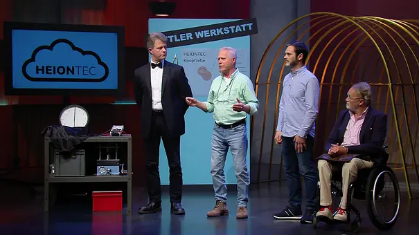 Vier Männer, einer im Rollstuhl, stehen beziehungsweise sitzen neben einem technischen Gerät und einem Bildschirm mit HEIONTEC-Logo. - Foto: RTL Vier Männer, einer im Rollstuhl, stehen beziehungsweise sitzen neben einem technischen Gerät und einem Bildschirm mit HEIONTEC-Logo. - Foto: RTL
