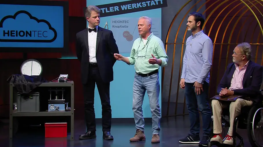 Ein Reinfall oder ein Milliardengeschäft? Das wird die Zukunft zeigen. Vier Männer, einer im Rollstuhl, stehen beziehungsweise sitzen neben einem technischen Gerät und einem Bildschirm mit HEIONTEC-Logo.