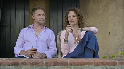 Ein Sommer auf Elba: Vor zwei grünen Holztüren sitzen Maja (Regula Grauwiller) und Thorsten (Janek Rieke) mit einem Glas Rotwein in den Händen auf der Terrasse. - Foto: ZDF / Christiane Pausch