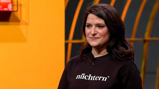 Isabella Steiner trägt ein schwarzes Oberteil mit dem weißen Schriftzug „nüchtern“ vor einem orange-schwarzen Hintergrund. - Foto: RTL Isabella Steiner trägt ein schwarzes Oberteil mit dem weißen Schriftzug „nüchtern“ vor einem orange-schwarzen Hintergrund. - Foto: RTL