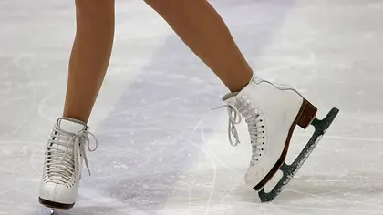 Zwei Beine in weißen Eiskunstlaufschuhen sind auf einer zerkratzten Eisfläche zu sehen. Ein Schuh ist seitlich angewinkelt. - Foto: iStock Zwei Beine in weißen Eiskunstlaufschuhen sind auf einer zerkratzten Eisfläche zu sehen. Ein Schuh ist seitlich angewinkelt. - Foto: iStock