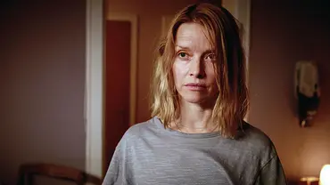 Karoline Schuch mit schulterlangen blonden Haaren und grauem T-Shirt blickt ernst zur Seite. Hinter ihr hängt ein Wandtelefon. - Foto: NDR/Sandra Höver Karoline Schuch mit schulterlangen blonden Haaren und grauem T-Shirt blickt ernst zur Seite. Hinter ihr hängt ein Wandtelefon. - Foto: NDR/Sandra Höver