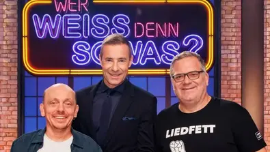 Kai Pflaume, Bernhard Hoëcker und Elton vor dem „Wer weiß denn sowas?“-Logo. - Foto: ARD/Morris Mac Matzen