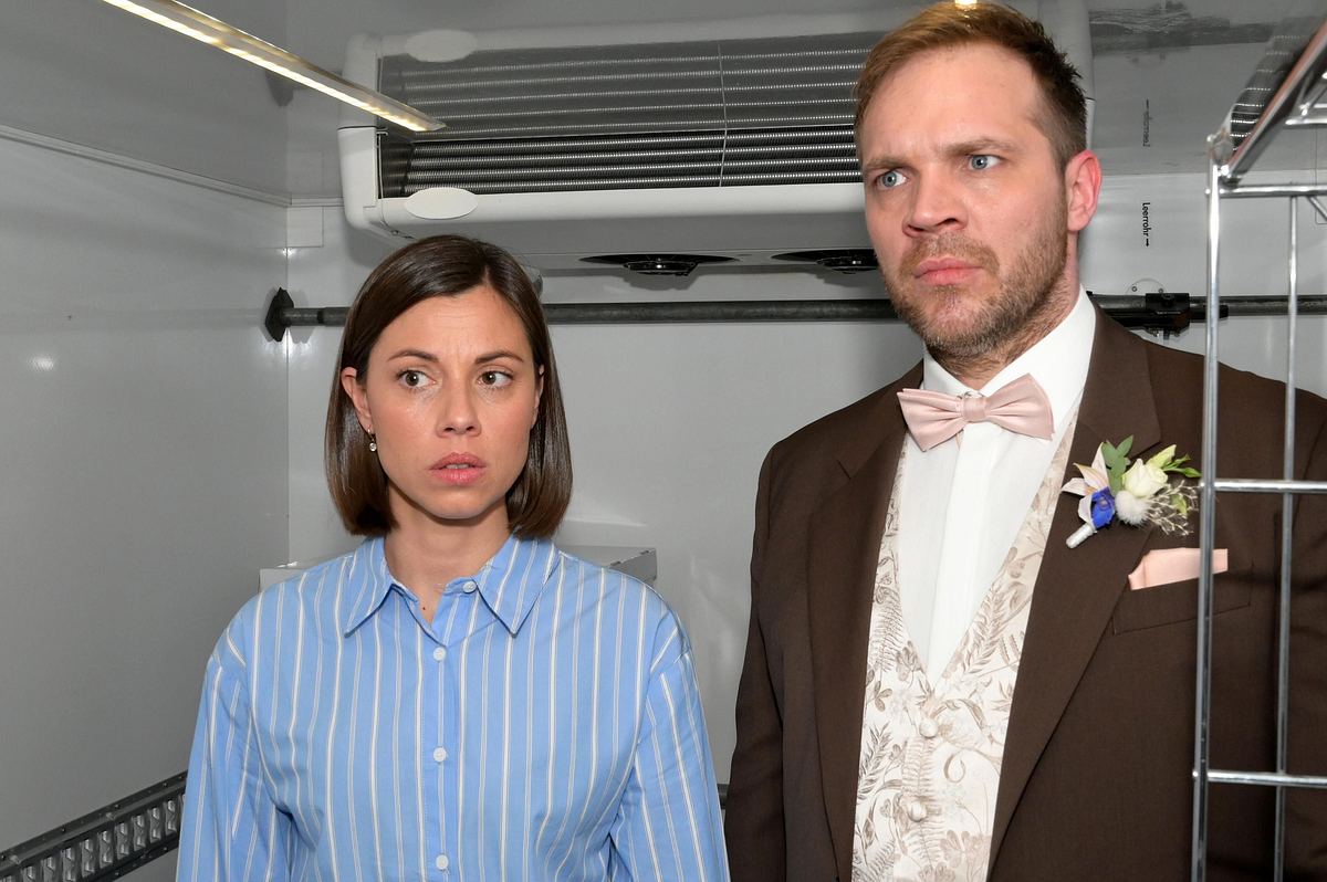 Matilda im blau-weißen Hemd und Erik im Anzug sind eingeschlossenen in einem Kühllaster.