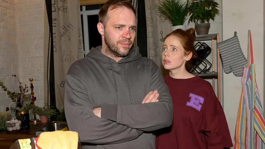 Erik muss Toni anlügen. Erik mit verschränkten Armen, während Toni ihn entsetzt anblickt.