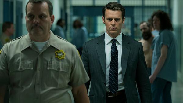 Holden Ford wird von einem Wachmann durch ein Gefängnis geführt. - Foto: Netflix