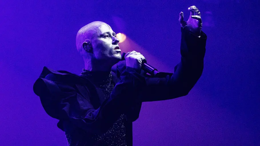 ESC 2025 Lion Ceccah Lion Ceccah steht vollständig silver angemalt auf der Bühne und hebt die rechte Hand.