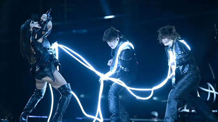 ESC 2026 Alexandra Căpitănescu Alexandra Căpitănescu hält leuchtende Seile, die um ihre Band gelegt sind.