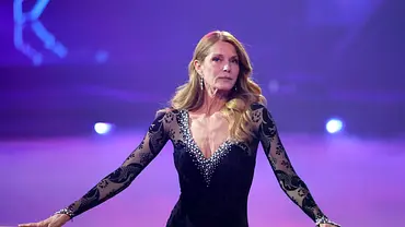 Esther Schweins steht an einer Barre, sie trägt ein schwarzes Kleid mit Spitze und blickt ernst. - Foto: IMAGO / Panama Pictures