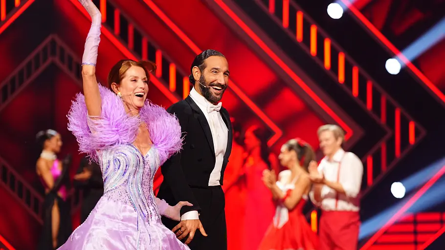 Esther Schweins und Massimo Sinató könnten den Kürzeren ziehen. Esther Schweins hebt den Arm, Massimo lacht neben ihr.