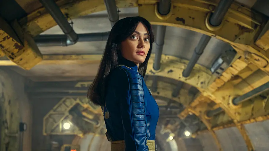 Fallout Staffel 1 Lucy Lucy steht in einem unterirdischen Vault und schaut in ihrem Fallout-Anzug Richtung Kamera
