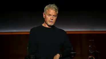 Eric Dane sitzt in schwarz in einem Rohlstuhl in einem Studio und schaut in die Kamera - Foto: Netflix
