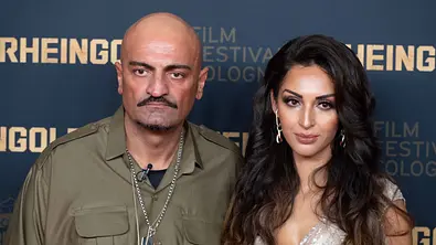 Xatar und Farvah: Beide blicken ernst in die Kamera und stehen vor einer Fotowand mit goldener Schrift beim Film Festival Cologne. - Foto: IMAGO / Sven Simon
