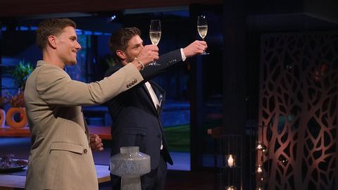 Martin Braun und Felix Stein bei der Rosenvergabe. In den Händen halten sie jeweils ein Sekt-Glas und stoßen an. - Foto: RTL+