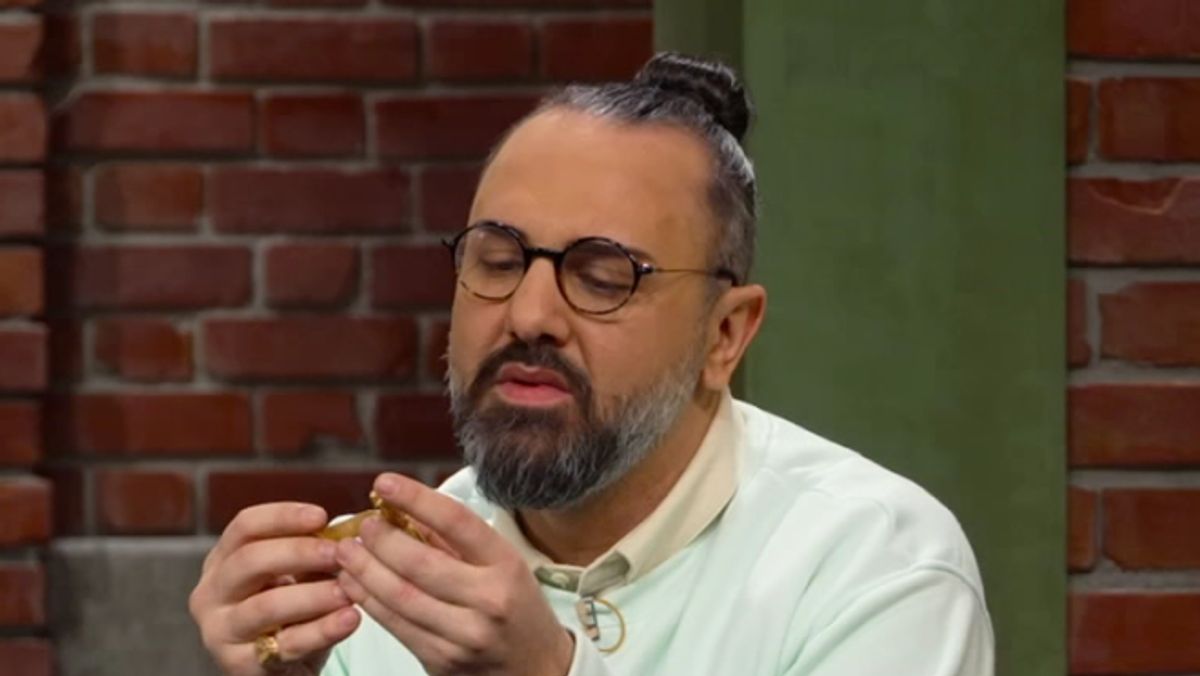 Ferdinand Resul Adanir untersucht ein goldenes Schmuckstück.