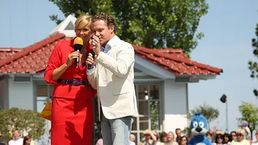Andrea Kiewel und Stefan Mross auf einer Bühne mit Mikrofonen in der Hand - Foto:  ZDF/Kerstin Bänsch