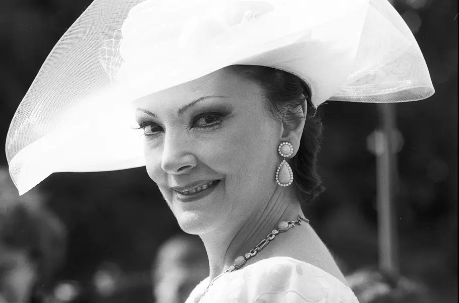 Anna Moffo lächelt in einer Schwarz-Weiß-Aufnahme mit großem hellem Hut, tropfenförmigen Ohrringen und Halskette.