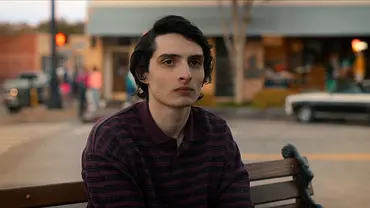 Finn Wolfhard sitzt als Mike auf einer Bank. - Foto: © 2025 Netflix, Inc.