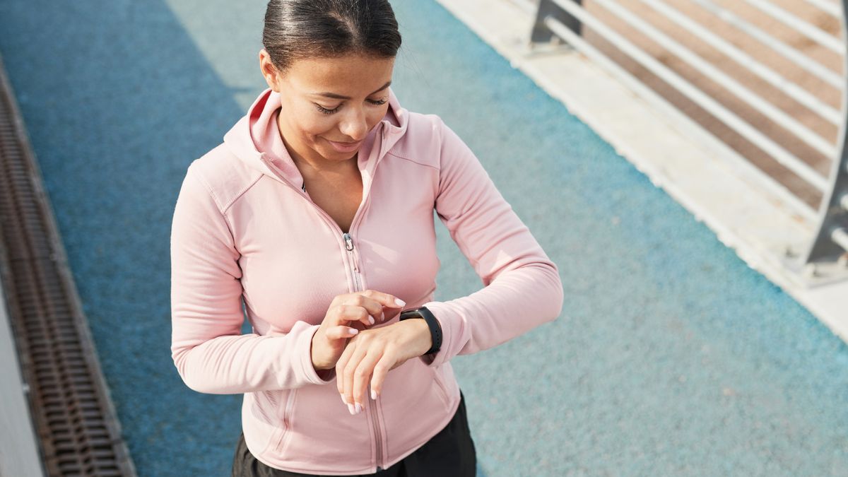 Fitnessarmband Stiftung Warentest Eine junge Frau in Sportkleidung schaut auf ihre Uhr.