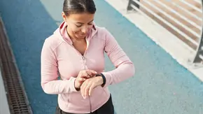Eine junge Frau in Sportkleidung schaut auf ihre Uhr.  - Foto: TVM/PR