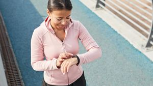 Eine junge Frau in Sportkleidung schaut auf ihre Uhr.  - Foto: TVM/PR