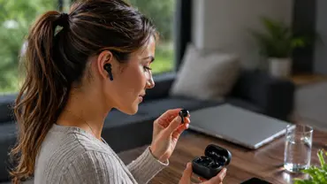 Eine Person richtet zu Hause ihre In-Ear-Kopfhörer ein und nimmt einen Ohrhörer aus dem Ladecase. Die Szene wirkt wie eine entspannte Vorbereitung auf Musik, Podcast oder ein Telefonat im Alltag. - Foto: KI-generiert / TV Movie Eine Person richtet zu Hause ihre In-Ear-Kopfhörer ein und nimmt einen Ohrhörer aus dem Ladecase. Die Szene wirkt wie eine entspannte Vorbereitung auf Musik, Podcast oder ein Telefonat im Alltag. - Foto: KI-generiert / TV Movie