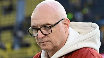 Frank Buschmann trägt eine Brille, einen weißen Hoodie und eine rote Jacke. Er blickt ernst nach unten. - Foto: IMAGO / Jan Huebner Frank Buschmann trägt eine Brille, einen weißen Hoodie und eine rote Jacke. Er blickt ernst nach unten. - Foto: IMAGO / Jan Huebner