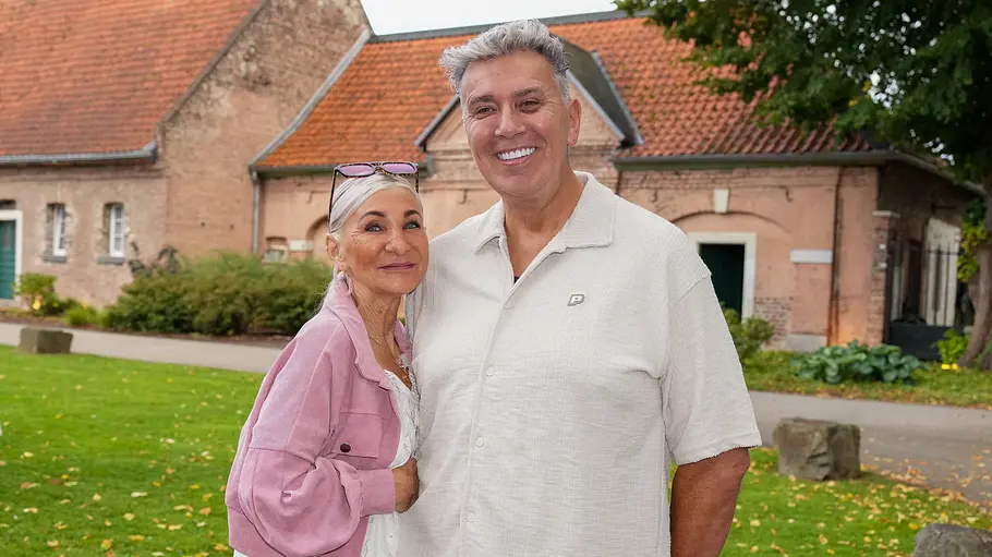 Frank und Elke Fussbroich Frank und Elke Fussbroich stehen lächelnd auf einer Wiese vor einem Backsteingebäude. Sie trägt eine rosa Jacke, er ein helles Hemd.