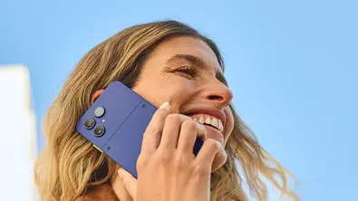 Frau telefoniert lachend mit einem Fairphone 6+ in Cobalt Blue vor blauem Himmel - Foto: Fairphone/PR Frau telefoniert lachend mit einem Fairphone 6+ in Cobalt Blue vor blauem Himmel - Foto: Fairphone/PR