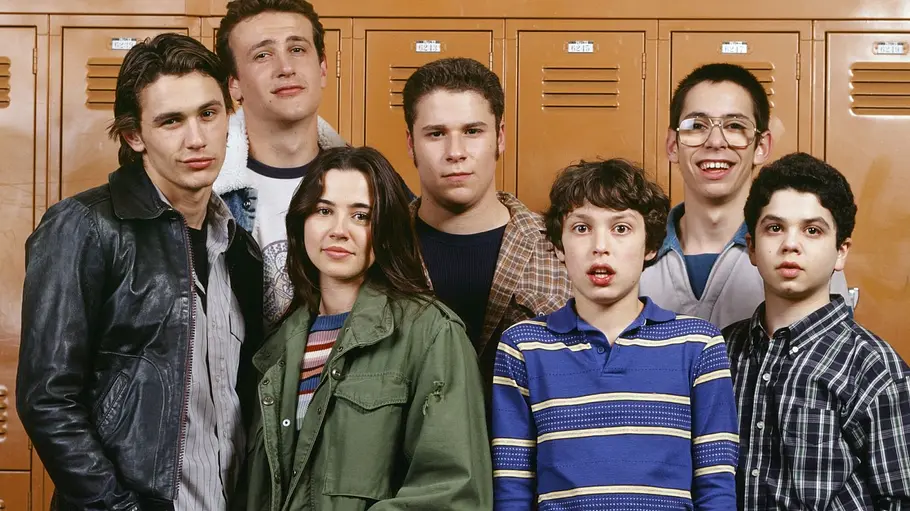 Freaks and Geeks Die Hauptfiguren der Comedyserie „Freaks and Geeks“ stehen gemeinsam vor einer Reihe orangefarbener Schließfächer in ihrer Highschool und blicken in die Kamera.