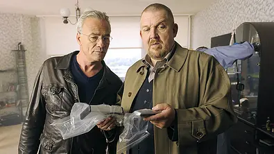 Max Ballauf und Freddy Schenk in Lederjacke und Mantel stehen in einem Zimmer und halten Gegenstände in durchsichtigen Plastiktüten. - Foto: WDR Max Ballauf und Freddy Schenk in Lederjacke und Mantel stehen in einem Zimmer und halten Gegenstände in durchsichtigen Plastiktüten. - Foto: WDR