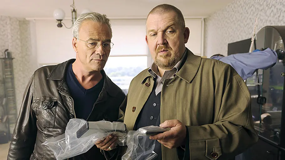 Freddy Schenk bekommt nach dem Aus von Max Ballauf eine neue Partnerin. Max Ballauf und Freddy Schenk in Lederjacke und Mantel stehen in einem Zimmer und halten Gegenstände in durchsichtigen Plastiktüten.
