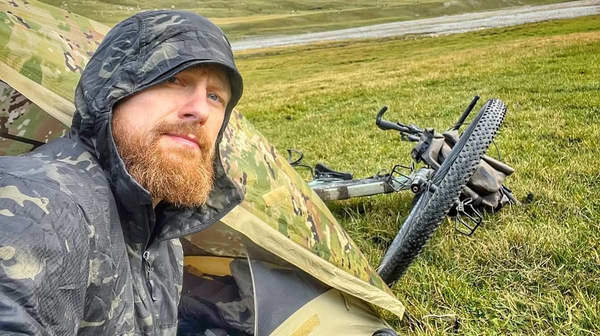Fritz Meinecke kehrt „7 vs. Wild“ den Rücken Ein Selfie von Fritz Meinecke zeigt ihn in einem Tarn-Outfit vor einem Zelt, im Hintergrund liegt ein Fahrrad im Gras
